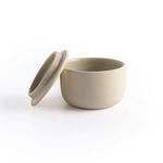 Open salt jar with lid resting beside it on white background