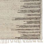 Zoomed detail of linear hand-knotted wool pattern with cream and taupe stripes and braided fringe