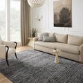 Soho Onyx / Silver rug shown in a living room beneath a beige sofa and armchair with neutral decor