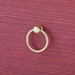 Detail of matte gold ring pull handle mounted on textured red drawer front