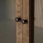 Close-up of round, dark metal knobs on glass panel cabinet doors