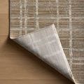Corner turned-up exposes the underside weave and structure of the rug on a wood floor