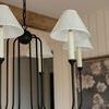 Close-up of three pleated shades and slender arms lit by daylight with wood beams overhead