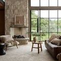 Rug laid out in bright living room with leather couch, wood table, large windows showing garden