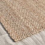 Corner view highlighting jute texture and edge laying on grey wood flooring