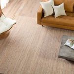 Top-down view of Rosier rug with wicker chair and leather sofa on light wood floor