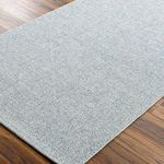 Close-up of Birdie denim rug on wooden floor showing flat woven texture and rectangular shape