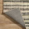 Backing of the rug flipped up, showing woven gray underside on a wood floor