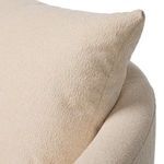 Close-up on the loose pillow with textured beige fabric tucked against chair back