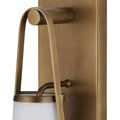 Close-up showing rounded end of wall plate and metal arm supporting top of shade in antique brass finish