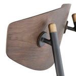 Close-up of backrest attachment with black metal support and brass caps on Kink Dining Chair