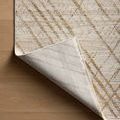 Rug corner lifted exposing underside with linear design visible on back