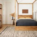 Reyla Granite Mocha Rug styled under wooden four-poster bed in modern bedroom with light wood flooring