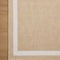 Flat lay close-up of Easton Wheat Ivory rug corner on wood floor highlighting border pattern and texture