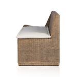 Side view showing bench profile with thick beige cushion on woven rattan frame