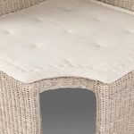Beige cushion seat detail with subtle tufting and rounded corner over rattan base