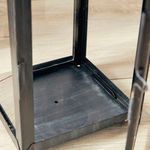 Close-up showing bottom interior of lantern with visible drain holes in powder-coated steel base