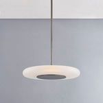Pendant light hanging straight down, illuminated with warm light against grey wall and white ceiling