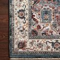 Samra Slate Multi rug with a traditional ornate pattern in slate blue, cream, rust, and beige tones on dark wood floor