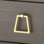 Detailed close-up of the gold trapezoid drawer pull hardware on the gray wood drawer front