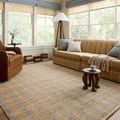 Rug placed in living room setting with beige sofa, leather chair, small wooden table, and window light