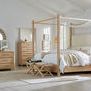 Wide shot of light-filled bedroom featuring Retreat rattan canopy bed with beige textiles and coordinating furniture