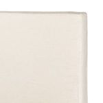 Close-up of wooden slat bed base under natural linen slipcover with fabric hem detail