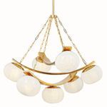Chandelier on white background with six seeded glass globes hanging from gold chains and curved gold metal frame