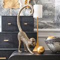 Gold hammered ball next to a bronze monkey figurine on a black console topped with black and white decor