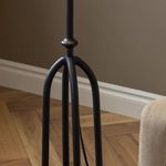 Close-up of black iron curved legs and part of floor with parquet wood and beige wall background