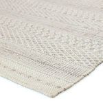 Close-up showing textured weave and detailed stitching on corner of cream and gray tribal rug