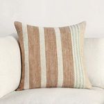 Pillow styled on white couch showcasing full striped front and knit accent