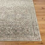 Corner view of rug showing edge binding and intricate border pattern on natural wood flooring.