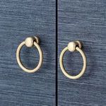 Close-up of gold finish ring pulls attached to cabinet doors with textured blue finish