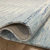 Close-up of curled edge of wool rug showing backing and thickness on hardwood floor