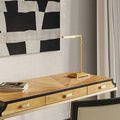 Desk setup featuring Autrand Desk Lamp on wood-finished desk beneath a black-and-white painting