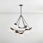 Chandelier lit with warm glow from six glass shades, viewed from slight side angle