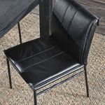 Close-up of Mayer chair seat and back in dining room setting on textured rug beside dark wooden table