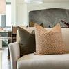 Olive velvet pillow styled on beige sofa with a patterned beige and white floral pillow in bright living room