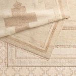 Stacked hand knotted rugs in varying beige tones showing different medallion and border patterns