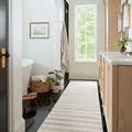 Narrow runner size of Chris Ivory Slate Rug in bright bathroom with black floor and wooden cabinetry