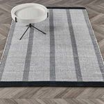 Rug styled under a modern round side table on chevron-patterned wood floor
