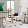 Lamp styled on console near white sofa in a bright room with gold-accented furniture and large windows