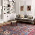Loren Blue / Red Rug shown in a living room setting with gray sofa, white built-in shelves, and modern artwork