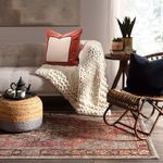 Rug styled in living room with ivory chunky knit throw on sofa and rattan chair with black pillow
