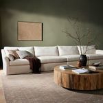 Sectional in styled living room setting with wooden round coffee table and textured pillows