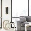 Partial sofa arm and cushion beside modern beige nested sculptural side tables by large window