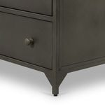 Bottom corner detail of dresser leg with slightly elevated metal foot and drawer edge
