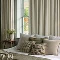 Plaid pillow styled on a bed among coordinating solid and floral pillows in a neutral bedroom setting