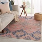 Traditional rug styled in living room with neutral sofa, pillows, wooden side table, and natural light